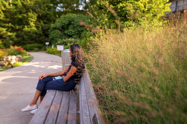 Foto seitenansicht einer frau, die in einem öffentlichen park auf einer parkbank sitzt
