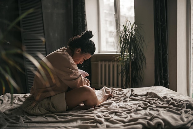 Seitenansicht einer Frau, die zu Hause auf dem Bett sitzt