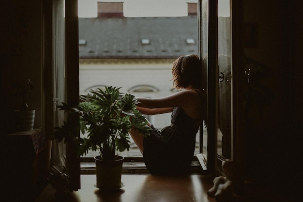 Seitenansicht einer Frau, die zu Hause durch das Fenster schaut