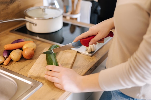 Seitenansicht einer Frau, die Zucchini auf einem Holzbrett schneidet Home-Food-Konzept