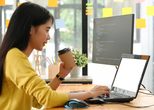 Seitenansicht einer Frau mit Laptop auf dem Schreibtisch im Büro