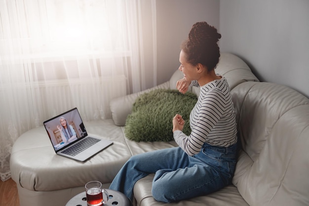 Seitenansicht einer fröhlich lächelnden Frau, die online im Video-Chat mit einer älteren Frau spricht