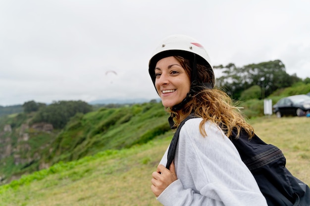 Seitenansicht einer fröhlichen Frau mit Gleitschirmausrüstung im Freien. Panoramablick auf eine abenteuerlustige Frau, die riskante Sportarten ausübt. Abenteuer und Sportlebensstil.