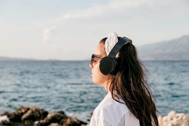 Seitenansicht einer jungen Frau am Strand, die Musik mit Kopfhörern hört Lifestyle Sommer