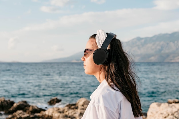 Seitenansicht einer jungen Frau am Strand, die Musik mit Kopfhörern hört Lifestyle Sommer