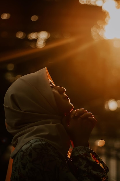 Foto seitenansicht einer jungen frau, die bei sonnenuntergang im freien betet