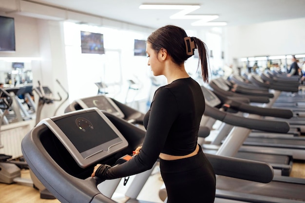 Seitenansicht einer jungen Frau, die ein Handy im Fitnessstudio benutzt