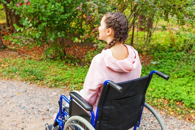 Foto seitenansicht einer jungen frau, die im park auf einem rollstuhl sitzt