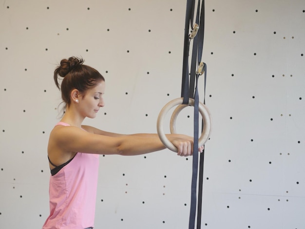 Seitenansicht einer jungen Frau, die mit Gymnastikringen trainiert