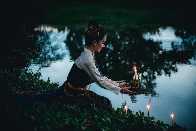 Seitenansicht einer jungen Frau mit einer Kerze am See sitzend