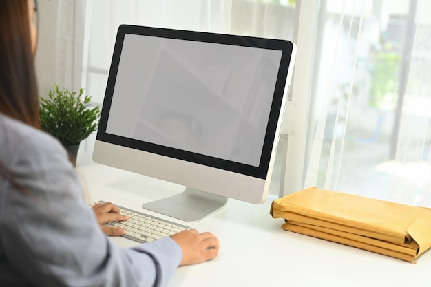 Seitenansicht einer jungen Geschäftsfrau, die an einem Schreibtisch sitzt und einen Computermonitor vor sich hat