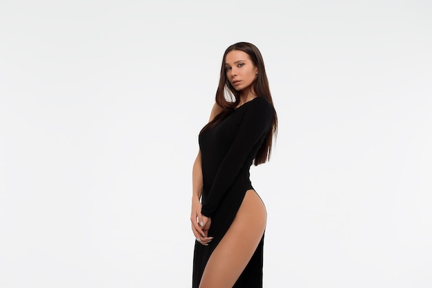 Seitenansicht einer sinnlichen Dame in sexy schwarzem Kleid, die vor weißem Hintergrund in die Kamera blickt