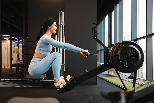 Seitenansicht einer Sportlerin beim Training auf dem Rudergerät