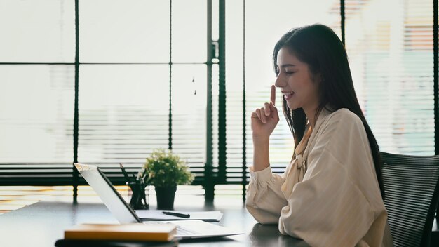 Seitenansicht einer Unternehmerin, die per Videokonferenz mit ihrem Geschäftspartner auf einem Laptop-Computer kommuniziert