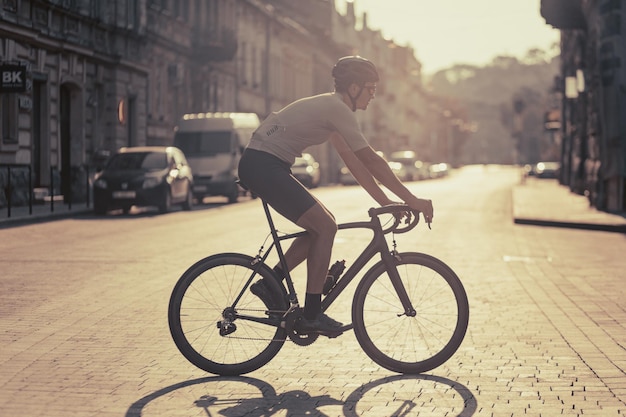 Seitenansicht eines aktiven jungen Mannes, der während der Morgenzeit Fahrrad auf der Stadtstraße fährt Kaukasischer Radfahrer trainiert regelmäßig, um fit und gesund zu bleiben Aktivitäten im Freien