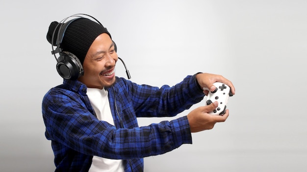 Foto seitenansicht eines asiatischen mannes, der spiele mit einem gamepad oder joystick auf einer konsole spielt