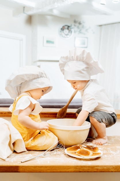 Seitenansicht eines charmanten kaukasischen kochjungen und -mädchens, das Teig für Pfannkuchen macht