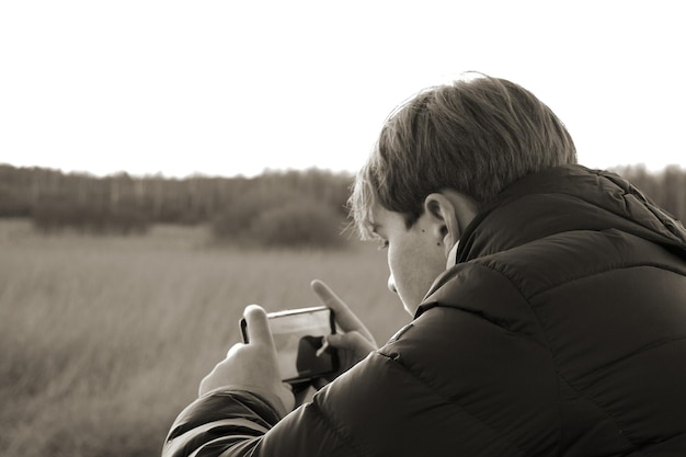 Foto seitenansicht eines jungen, der ein handy benutzt