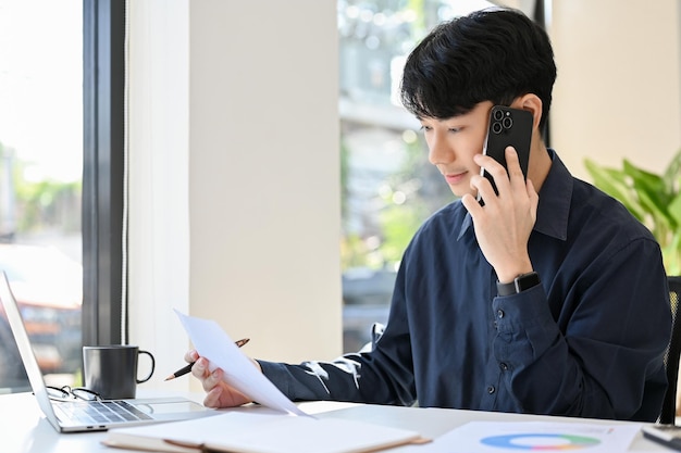 Seitenansicht eines jungen Geschäftsmannes, der während der Arbeit mit einem Kunden telefoniert