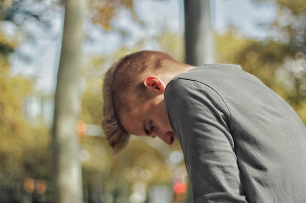 Seitenansicht eines jungen Mannes, der gegen Bäume steht
