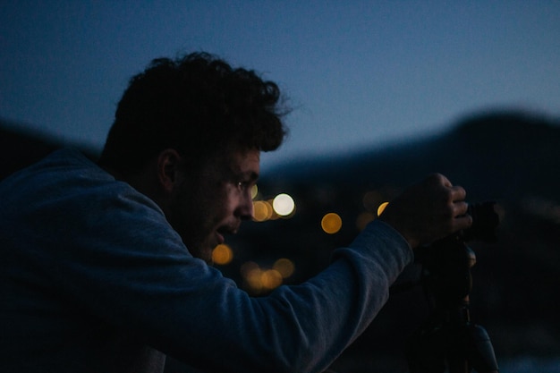 Seitenansicht eines jungen Mannes mit einer Lampe in der Nacht