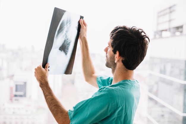 Foto seitenansicht eines männlichen doktors, der röntgenstrahl betrachtet