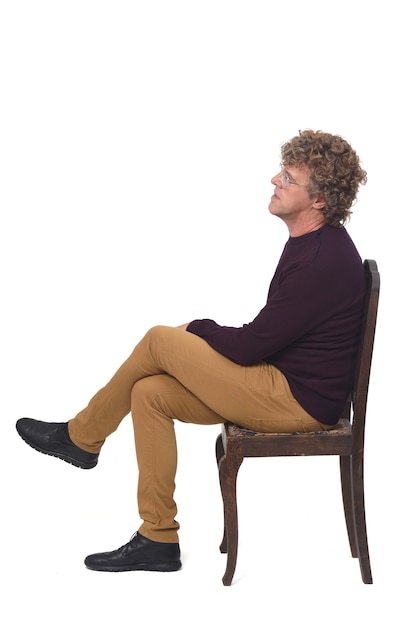 Seitenansicht eines Mannes, der auf weißem Hintergrund sitzt, die Beine gekreuzt
