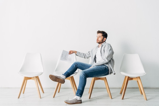 Seitenansicht eines Mannes mit Lebenslauf, der auf einem Stuhl im Büro sitzt