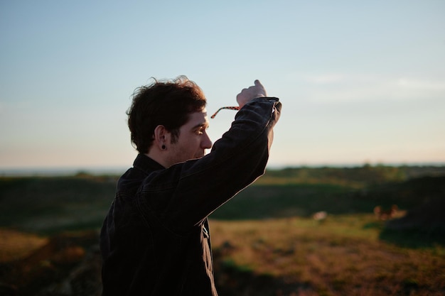 Seitenansicht eines Mannes mit Sonnenbrille, der gegen die Landschaft steht und wegblickt