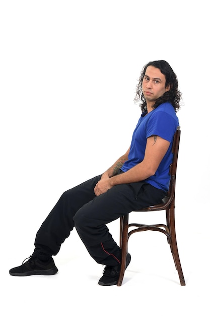 Seitenansicht eines Mannes mit Sportkleidung, der auf einem Stuhl sitzt und auf weißem Hintergrund in die Kamera schaut