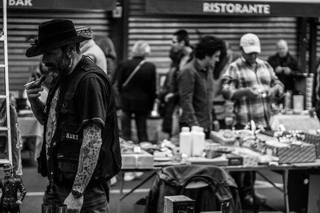 Foto seitenansicht eines reifen mannes, der auf dem straßenmarkt zigaretten raucht.