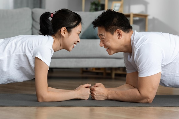 Seitenansicht eines sportlichen asiatischen Mannes und einer Frau, die zusammen Planken