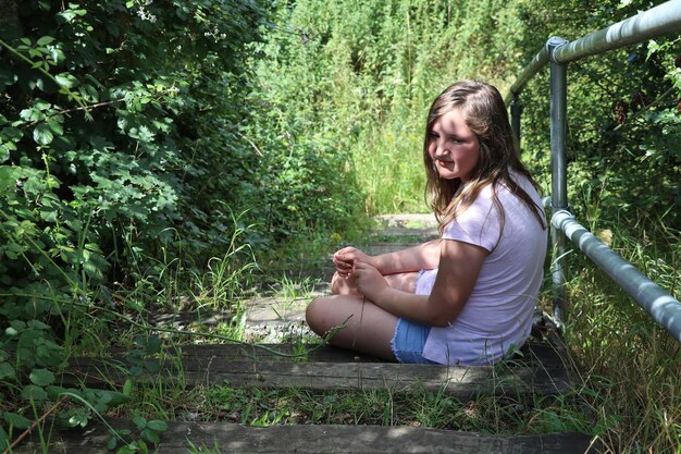 Foto seitenansicht eines teenager-mädchens, das auf dem feld sitzt