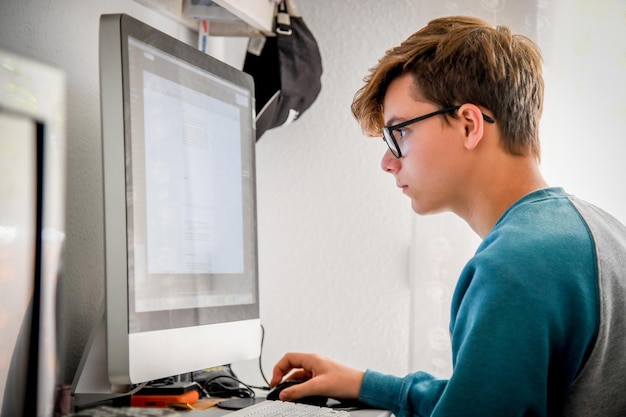 Seitenansicht eines Teenagerjungen, der zu Hause einen Computer benutzt