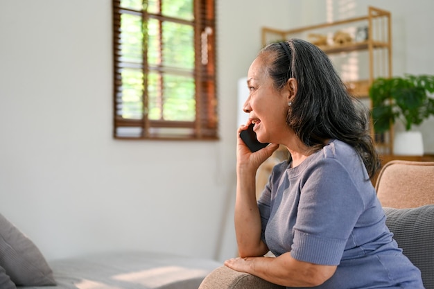 Seitenansicht Glückliche asiatische 60-jährige Frau spricht am Telefon mit jemandem