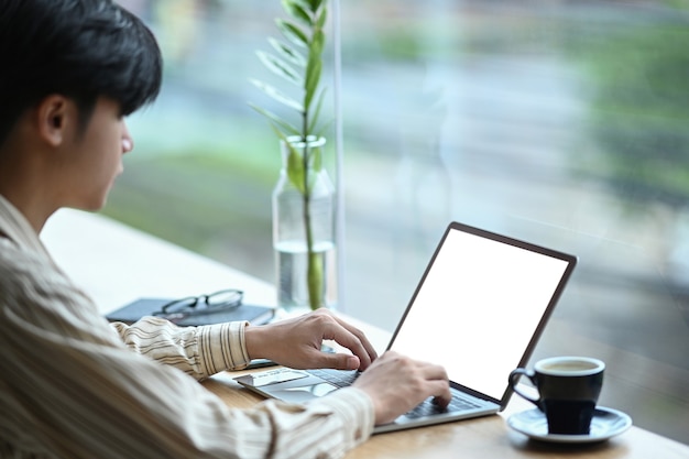 Seitenansicht männlicher Freiberufler, der mit Computer-Laptop im Café arbeitet.