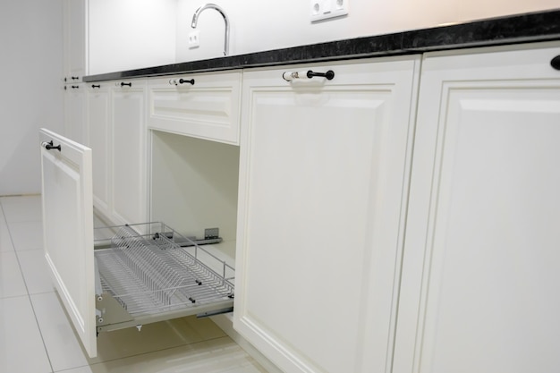 Foto seitenansicht moderne und elegante küche mit weißen schubladen offene küchenschublade mit selektivem fokus auf geschirrtrockner