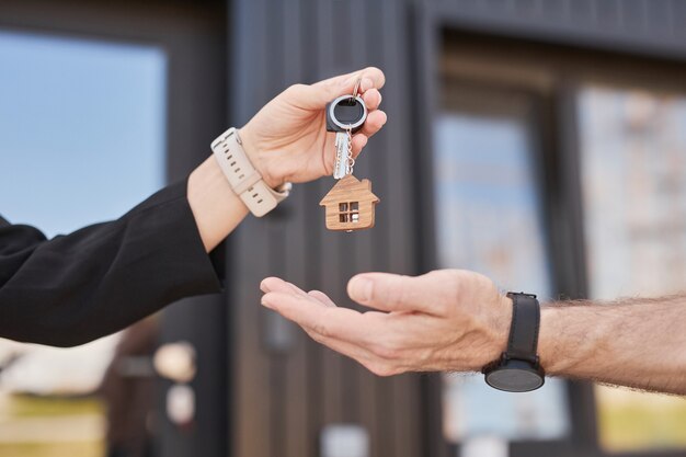 Seitenansicht, Nahaufnahme einer Immobilienmaklerin, die dem Kunden im Freien Schlüssel übergibt, Platz kopieren