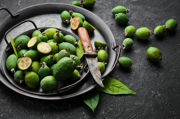 Seitenansicht natürlicher frischer grüner Feijoas auf schwarzem Steinhintergrund