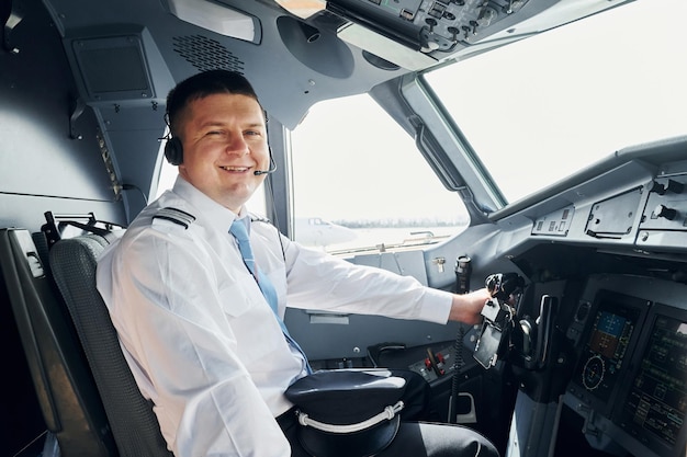Seitenansicht Pilot in formeller Kleidung sitzt im Cockpit und steuert Flugzeug