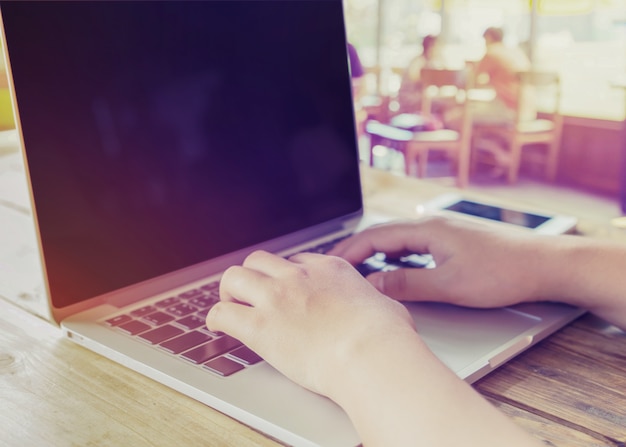 Foto seitenansicht schuss von schönen jungen hipster frau hände beschäftigt arbeiten an ihrem laptop sitzen am holztisch in einem coffee-shop - retro-filter-effekt und vintage-farb-stil