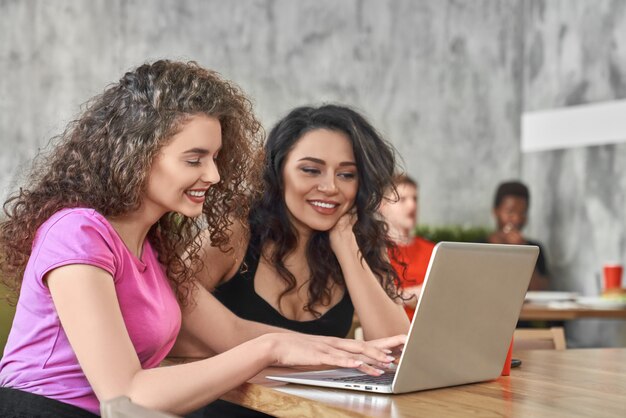 Seitenansicht von den Freiberuflern, die online im Café arbeiten. Zwei Kollegen, die mit Computer arbeiten