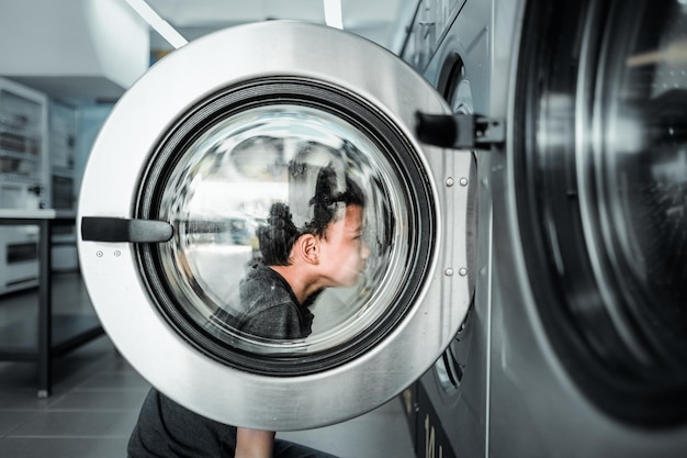 Seitenansicht von einem Jungen, der sich eine Waschmaschine in einem Waschsalon ansieht