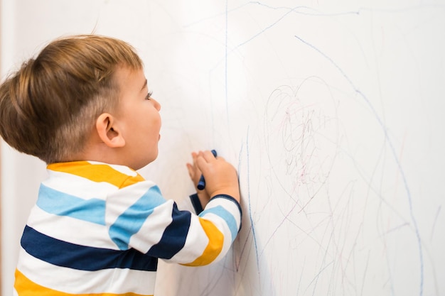 Seitenansicht von einem süßen Jungen, der ein Gemälde an der Wand hält