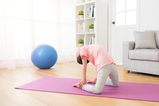 Seitenansicht von Mädchen, die Yoga-Aktionen praktizieren, knien Sie im Trainingsraum nieder und machen Sie Yoga-Pose, die Sportkleidung im Innenbereich auf Weltraumhintergrund trägt.