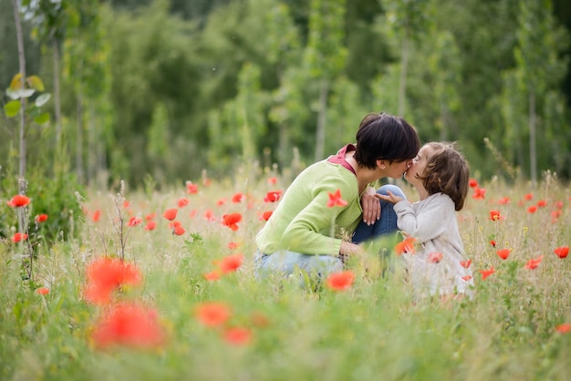 Seitenansicht von Mutter und Tochter, die sich auf einem grasbewachsenen Feld küssen