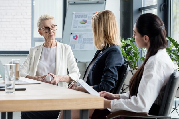 Seitenansicht von schönen Geschäftsfrauen, die sich bei einem Meeting im Büro unterhalten