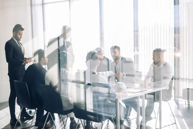 Seitenansicht von unscharfen Silhouetten von Geschäftsleuten, die im Konferenzraum sprechen