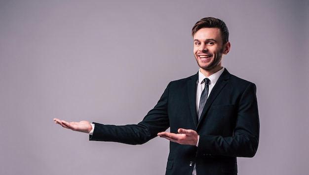 Seitenansichtfoto des stilvollen, eleganten und selbstbewussten jungen Geschäftsmannes zeigt weg isoliert auf grauem Hintergrund