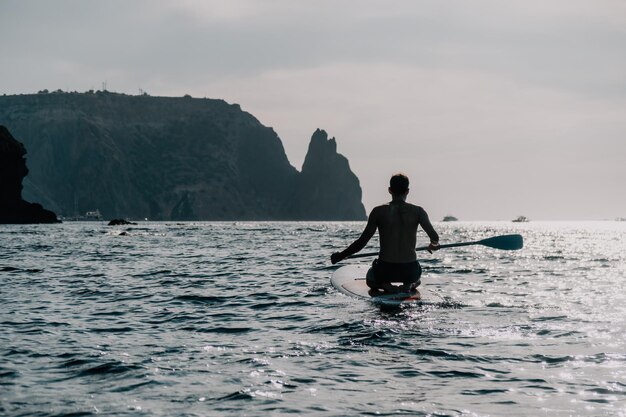 Seitenansichtfoto eines Mannes, der auf dem SUP-Board schwimmt und sich entspannt sportlicher Mann im Meer auf dem Stand